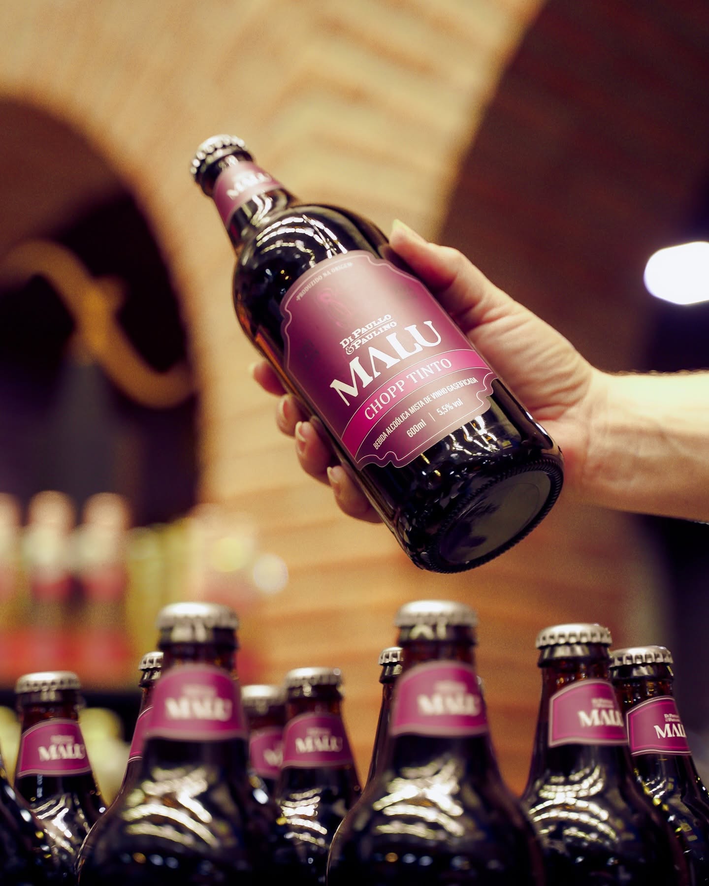 Garrafa de chopp tinto Malu apresentada sobre outras garrafas